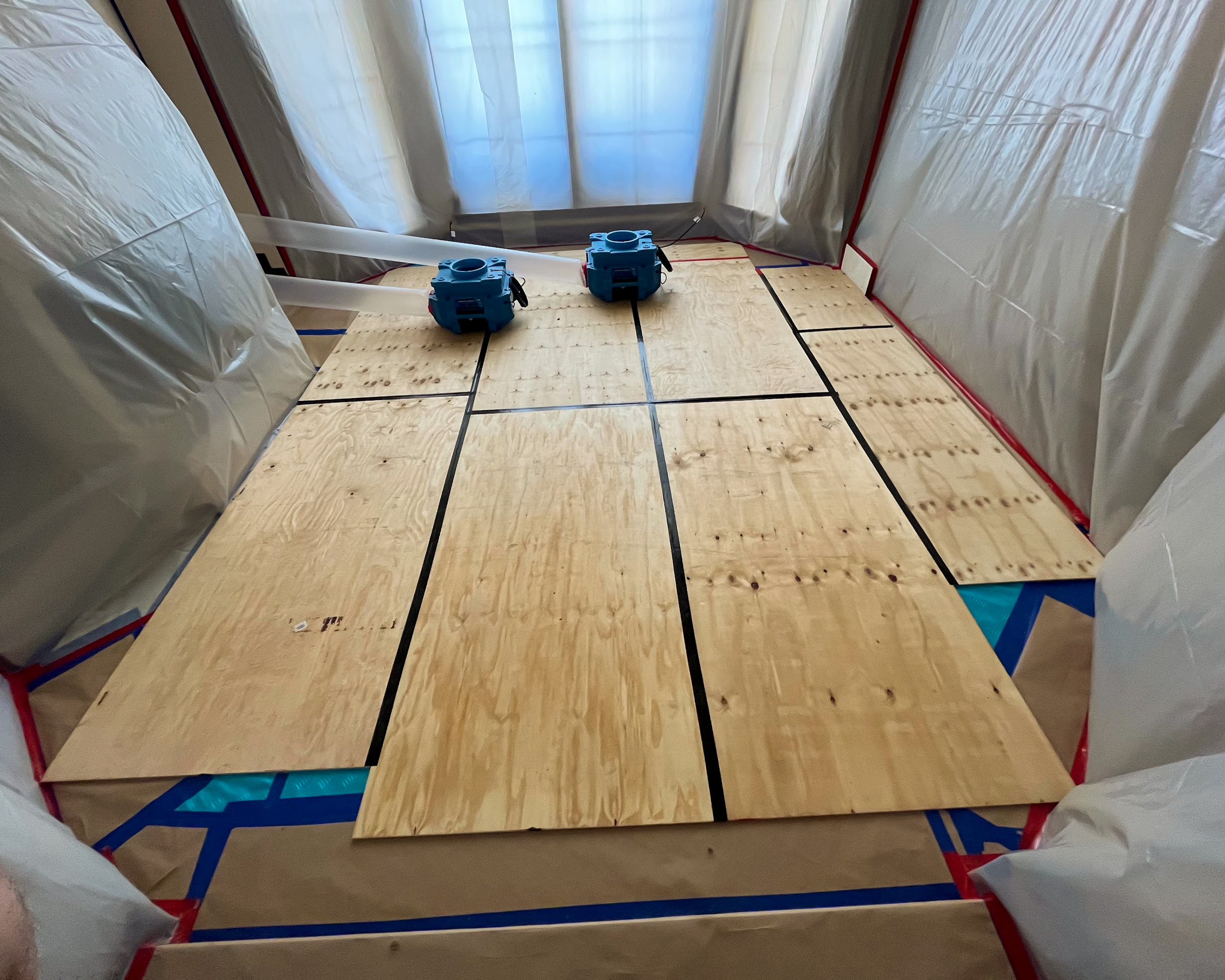 Blue air movers on plywood inside containment area