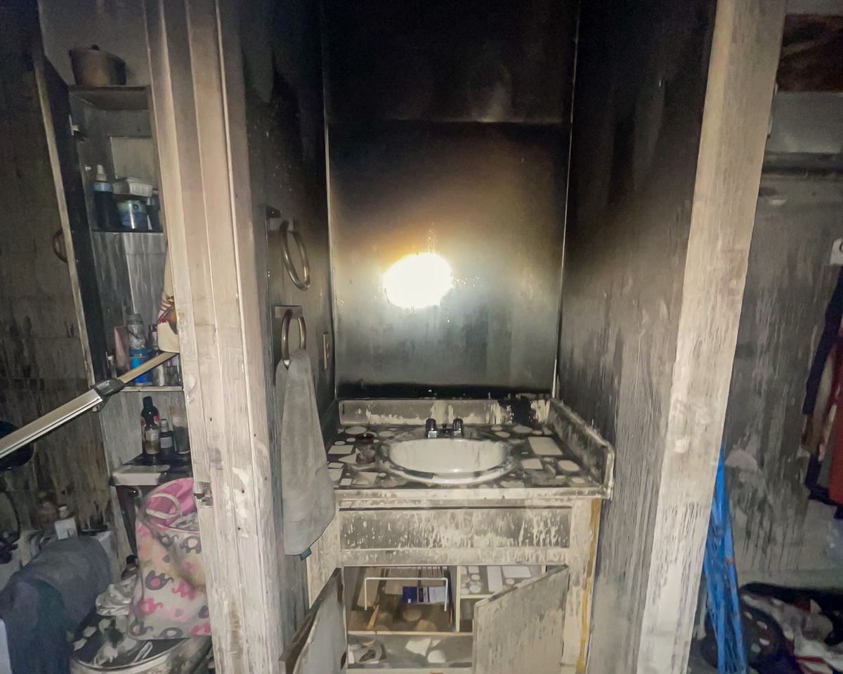 Fire-damaged bathroom, soot-stained mirror and sink