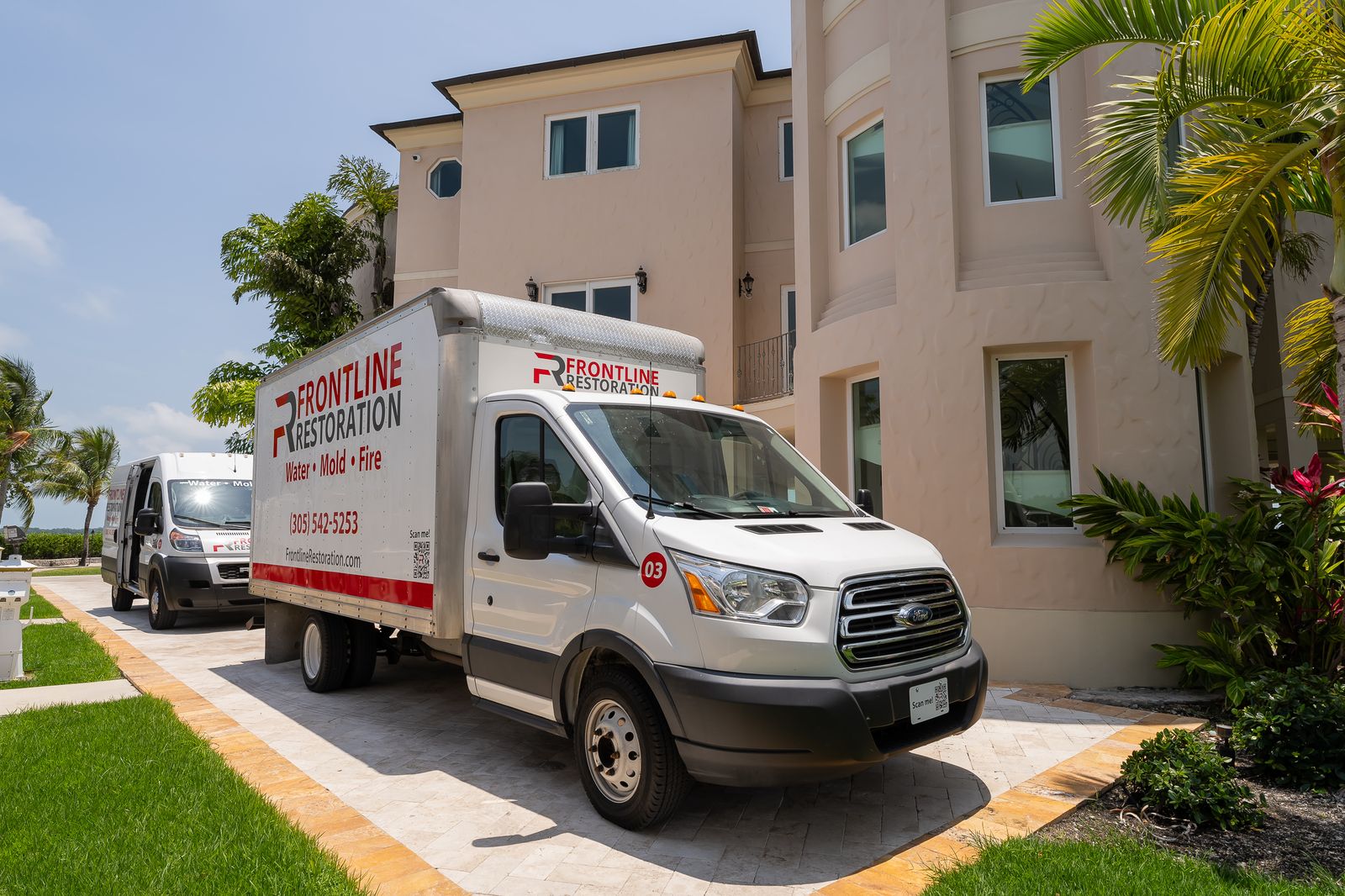 Frontline Restoration box truck and van parked at a large residential property
