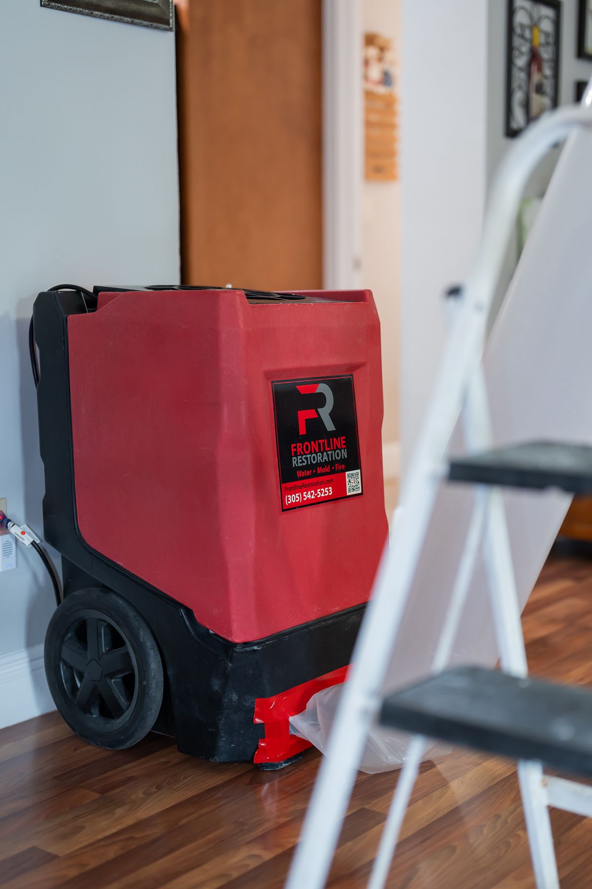 Dehumidifier running next to a ladder inside a home