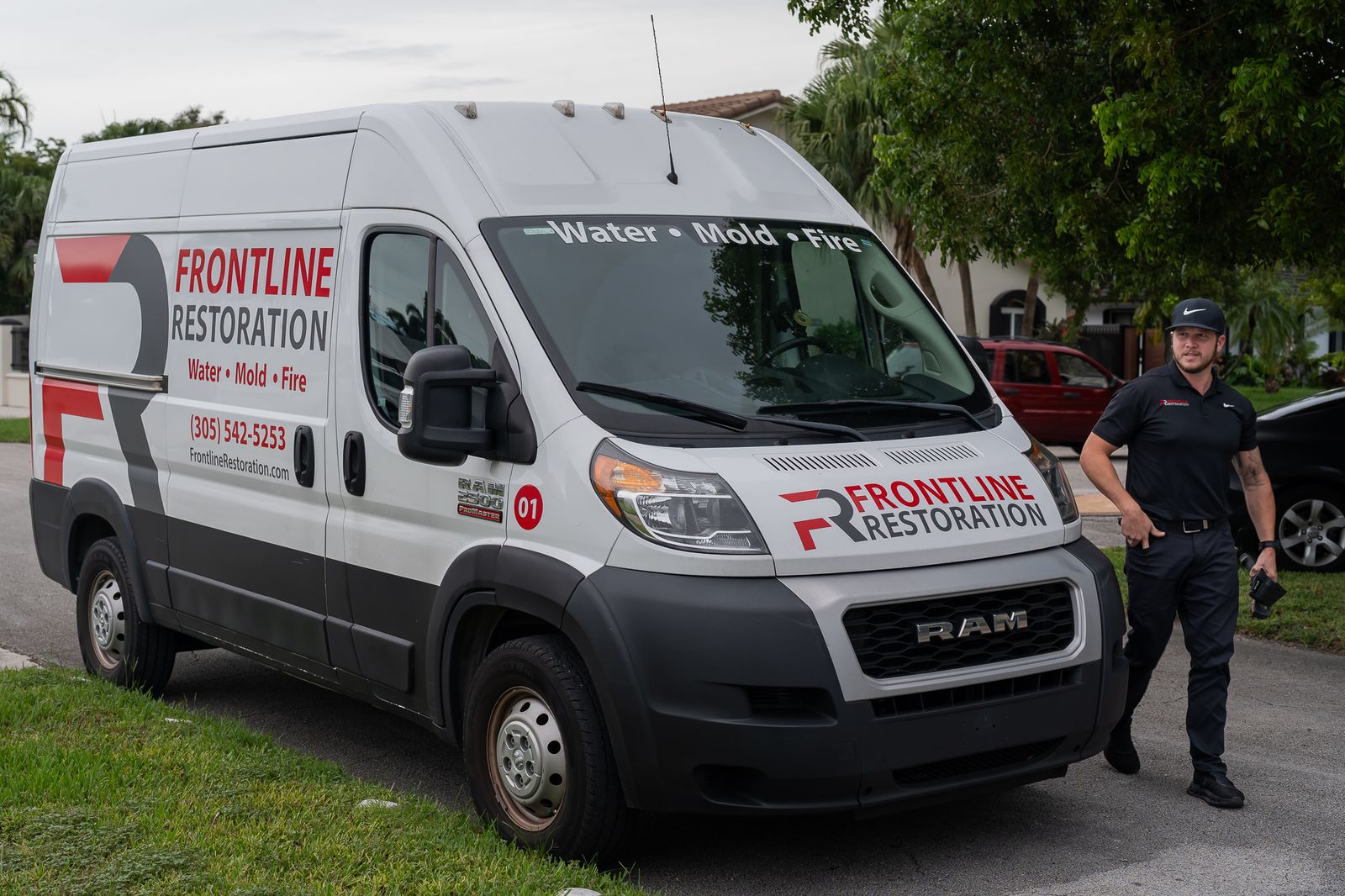 Frontline Restoration van at the curb with a technician walking to the property